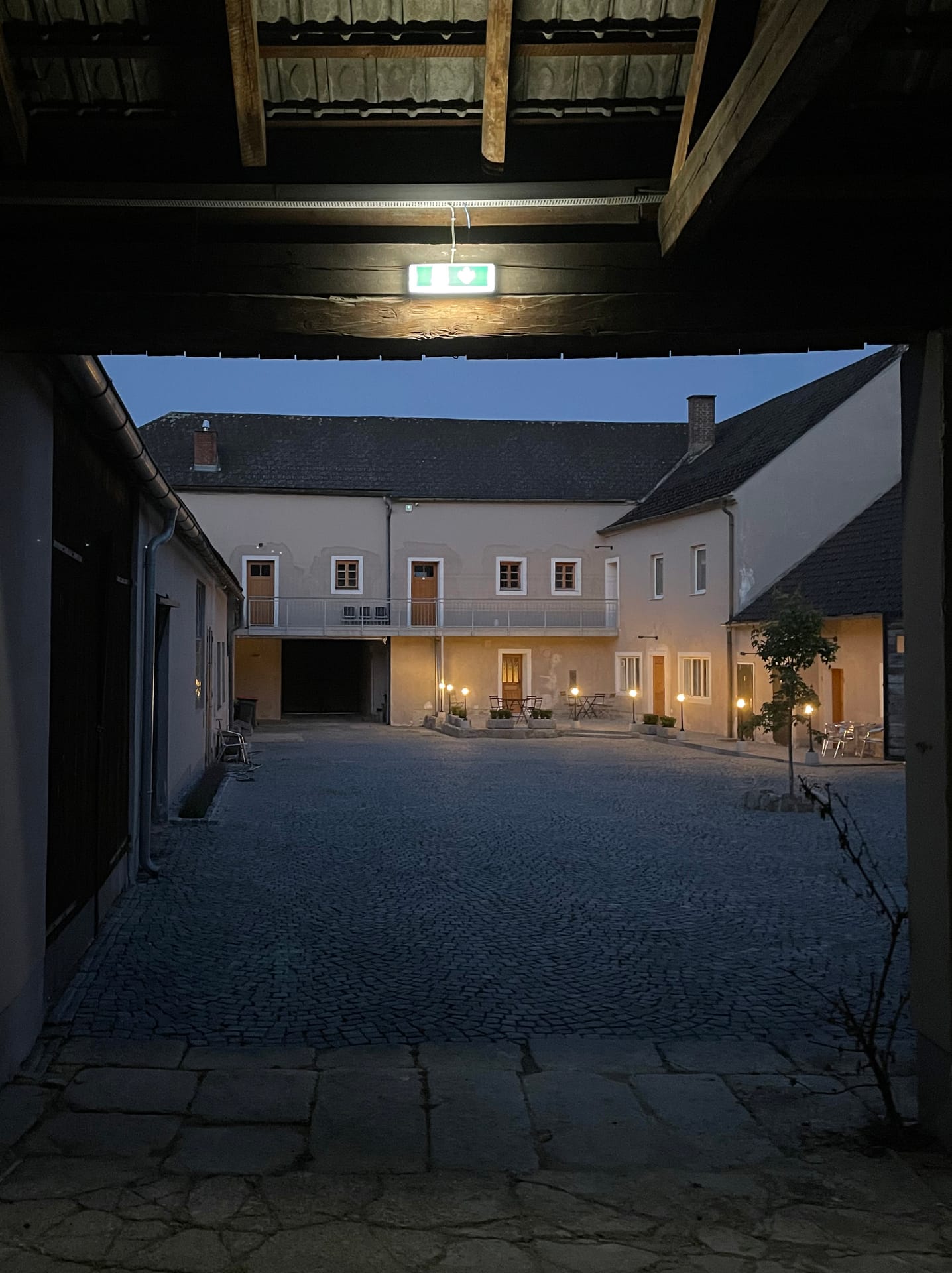 Innenhof mit Einfahrt und beleuchteten Fenstern am Abend