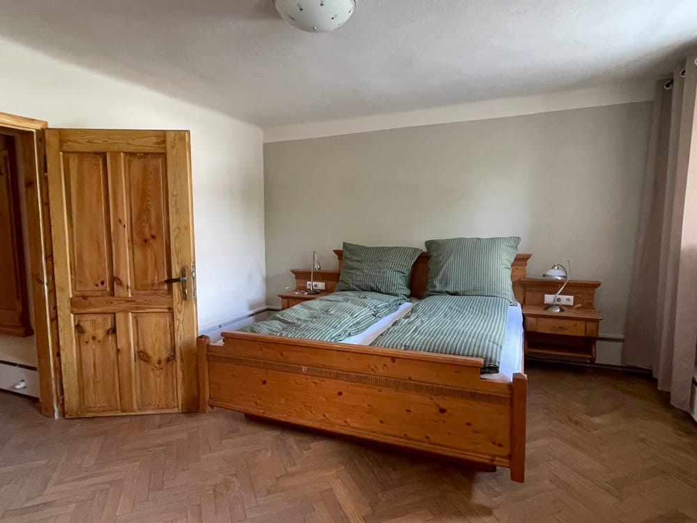 Zimmer mit Doppelbett aus Kiefernholz und grün gestreiften Kissen