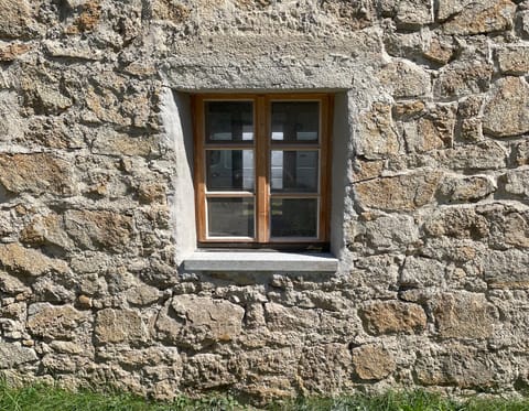 Kleines Holzfenster in massiver Natursteinmauer