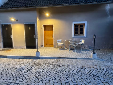 Innenhof am Abend mit beleuchteten Türen und Bistrotisch