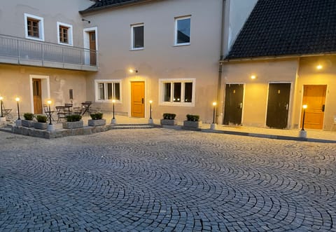 Gepflasterter Innenhof mit Sitzplätzen und Laternen am Abend