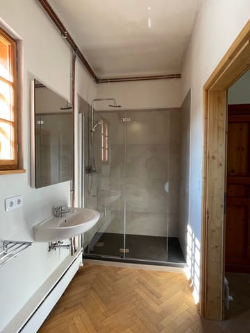 Badezimmer mit Waschbecken, Spiegel und Duschkabine