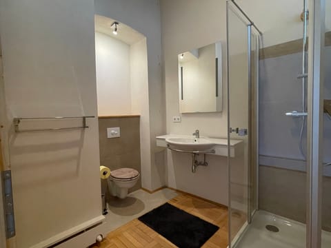 Badezimmer mit Glasdusche, Waschbecken und Wand-WC
